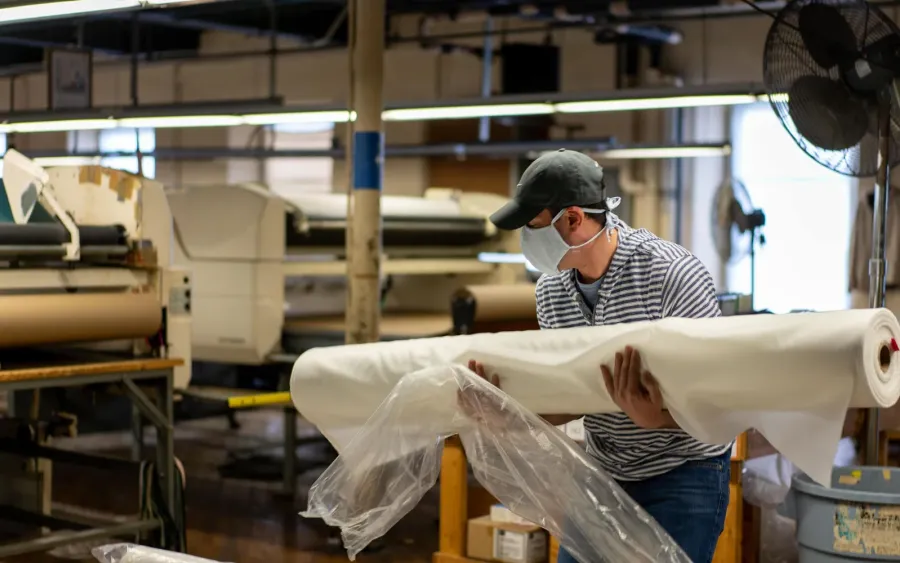 Textile factory worker handling fabric rolls for manufacturing control